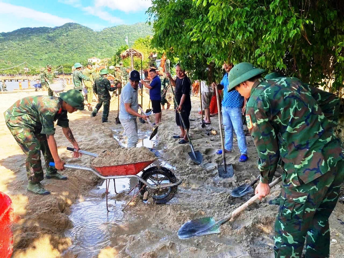 Bộ đội giúp dân&nbsp;xã đảo Tân Hiệp dọn dẹp bùn đất sau bão số 13. Ảnh Tấn Thành.