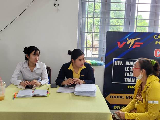 Nhân viên Ngân hàng tuyên truyền, vận động người hưởng lương hưu chuyển đổi sang thanh toán không dùng tiền mặt tại Phường Trấn Biên. Ảnh: HT