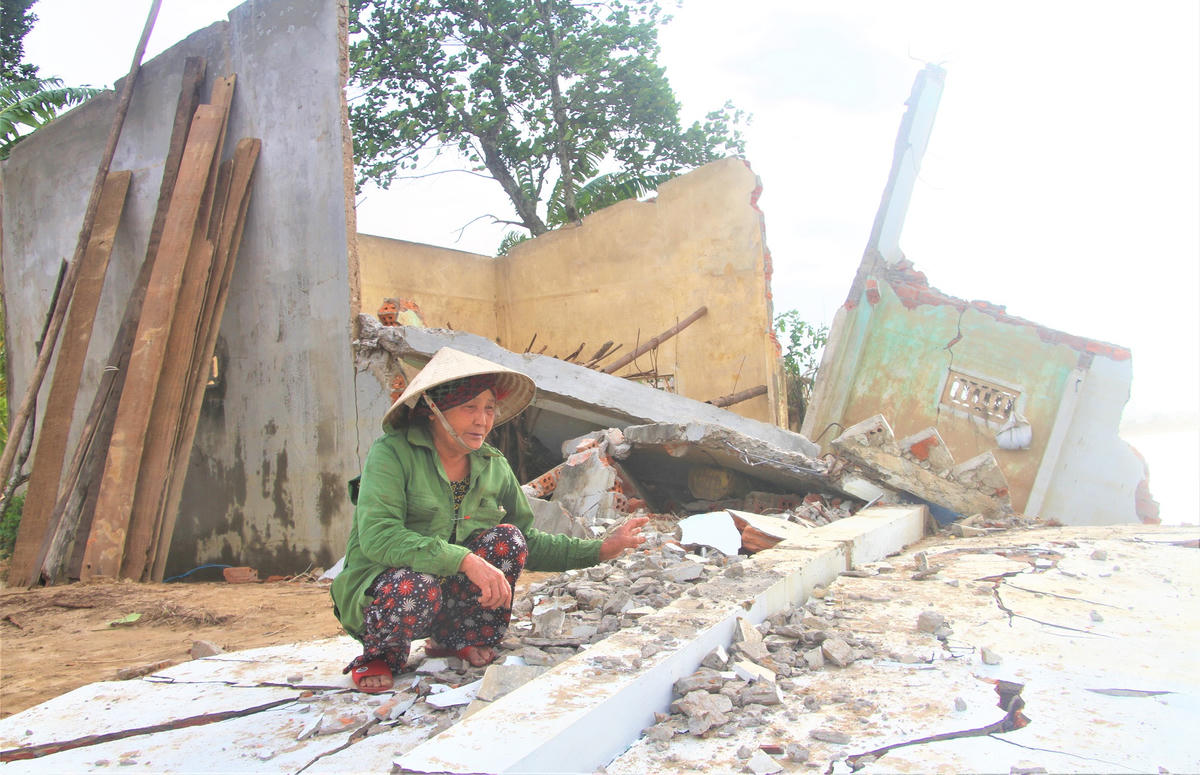 Bà Phan Thị Mãn đau xót khi nhìn ngôi nhà sập đổ, đất vườn bị sạt lở xuống sông Vu Gia. Ảnh: Tấn Thành.