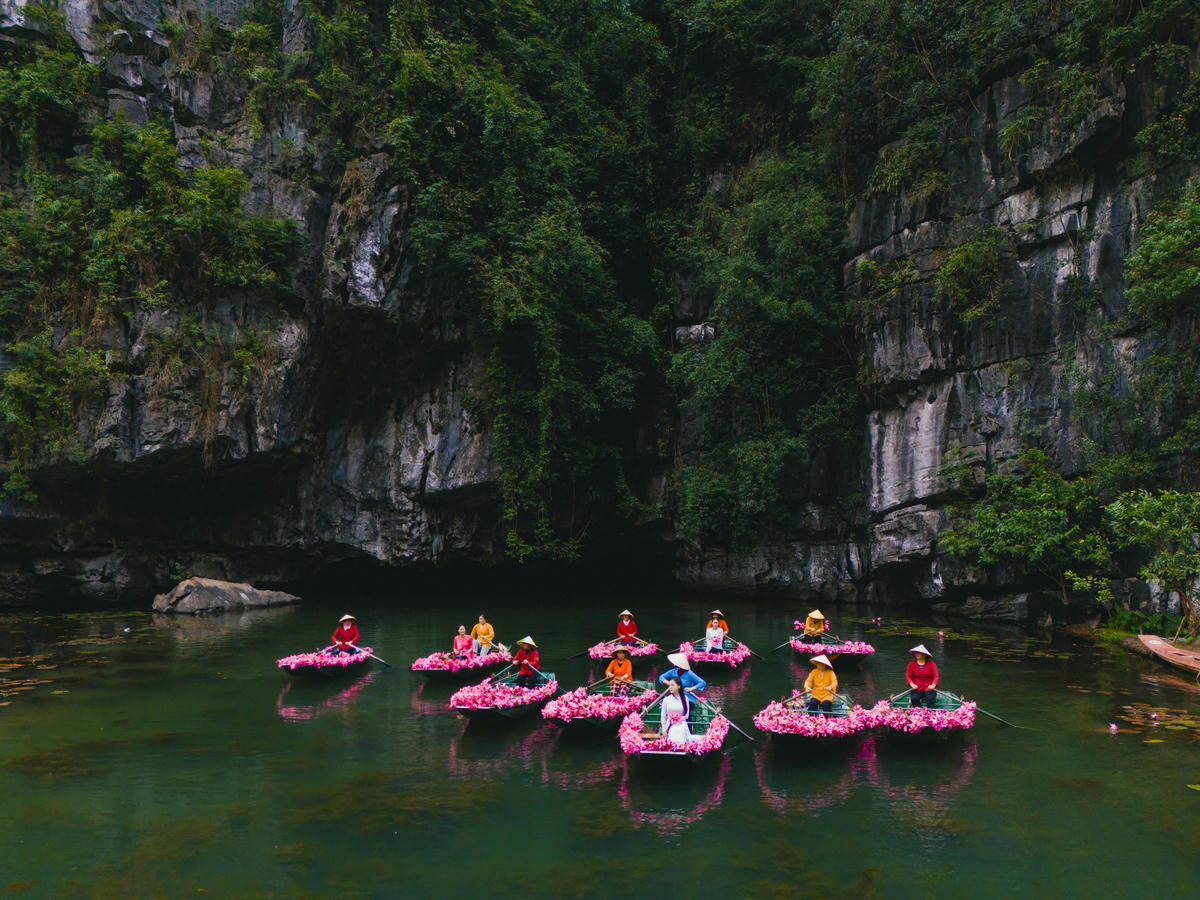 Hai bên bờ là núi đá vôi xanh thẳm, dưới là thảm hoa tím trải dài, tiếng mái chèo khua nhẹ hòa cùng tiếng chim gọi ban mai, tạo nên khung cảnh vừa yên bình vừa lãng mạn. Ảnh: Ngọc Linh