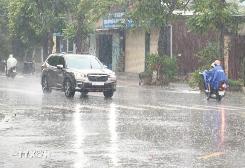 Người dân đi lại trong mưa lớn. (Ảnh: Nguyên Lý/TTXVN).