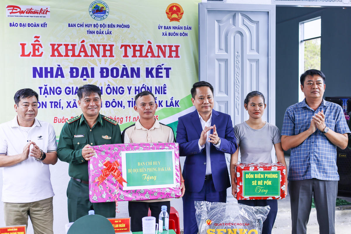 Nhà báo Trương Thành Trung, Tổng Biên tập Báo Đại đoàn kết  và Đại tá Rơ Lan Ngân, Phó Chính ủy Bộ Chỉ huy Bộ đội Biên phòng tỉnh Đắk Lắk tặng quà cho gia đình ông Y Hớn Niê. Ảnh: Quang Vinh.