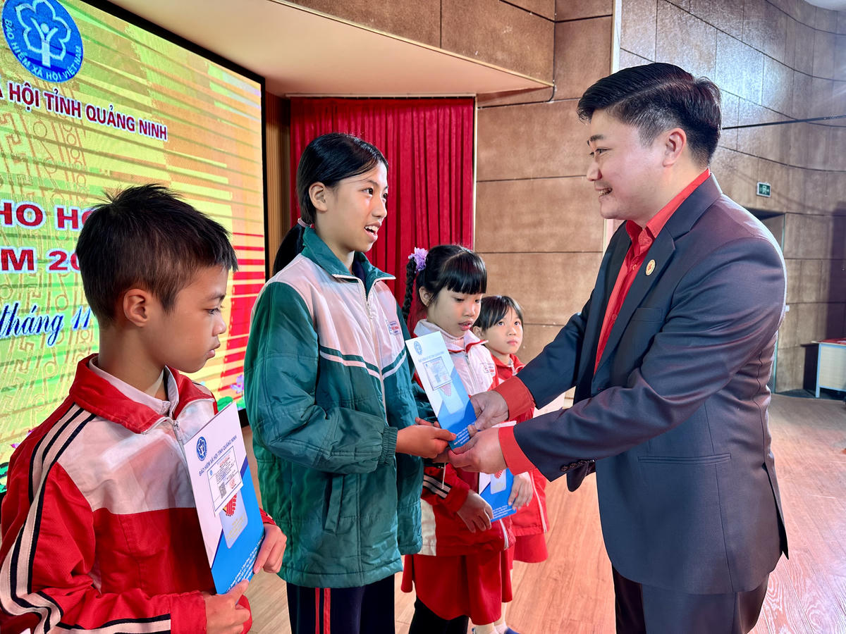 Ông Lý Văn Thành, Chủ tịch Hội Chữ thập đỏ tỉnh Quảng Ninh trao thẻ BHYT cho các em học sinh. Ảnh: Ngọc Anh.