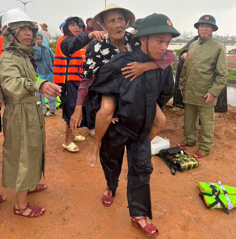 Chiến sĩ của Bộ CHQS tỉnh Gia Lai còng người già ở xã Tuy Phước vùng ngập lụt đến nơi an toàn. Ảnh: CV.