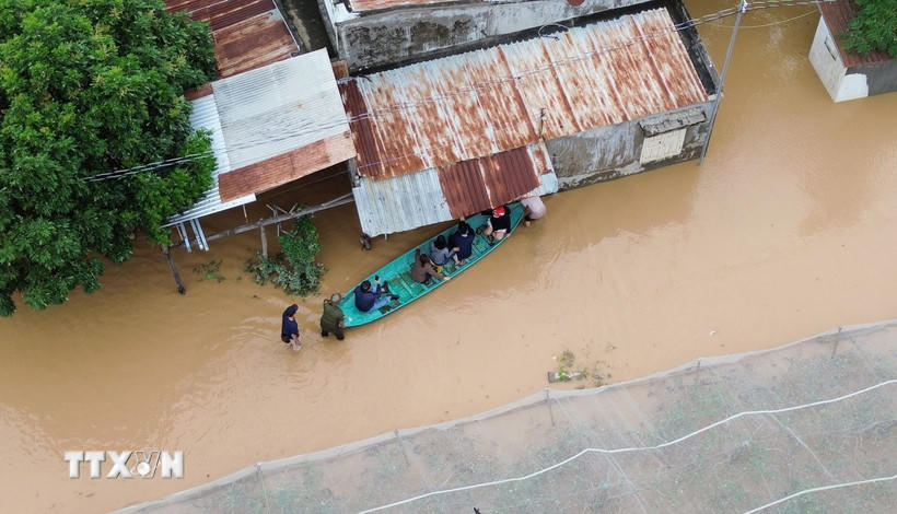 Người dân di chuyển bằng thuyền tại khu vực ngập nước tại xã Ninh Phước (Khánh Hòa). (Ảnh: Nguyễn Thành/TTXVN).