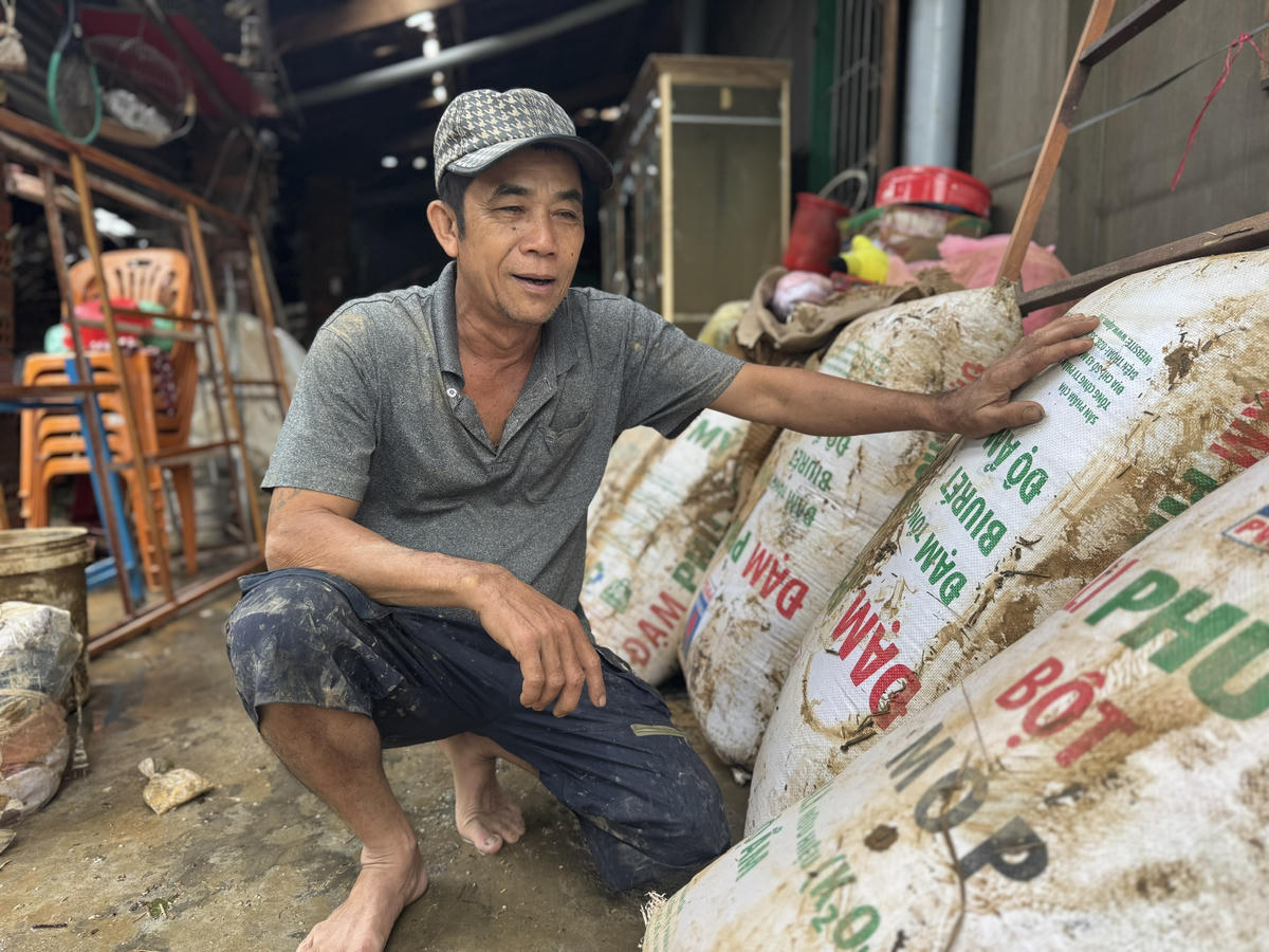 Ông Lê Kim Hồng (55 tuổi) cũng trở về trong cảnh ngổn ngang, ngồi bên đống lúa ướt nhẹp, hư hại (Ảnh: Đình Sang)