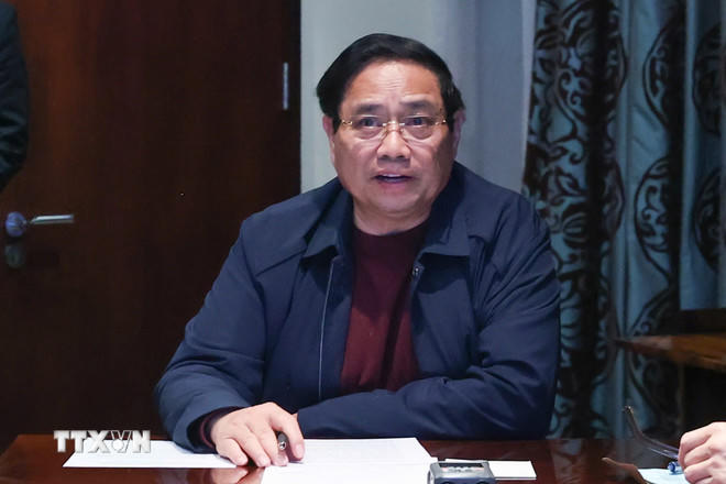 Thủ tướng Phạm Minh Chính chủ trì họp trực tuyến từ Nam Phi, chỉ đạo khắc phục hậu quả mưa lũ. (Ảnh: Dương Giang/TTXVN).