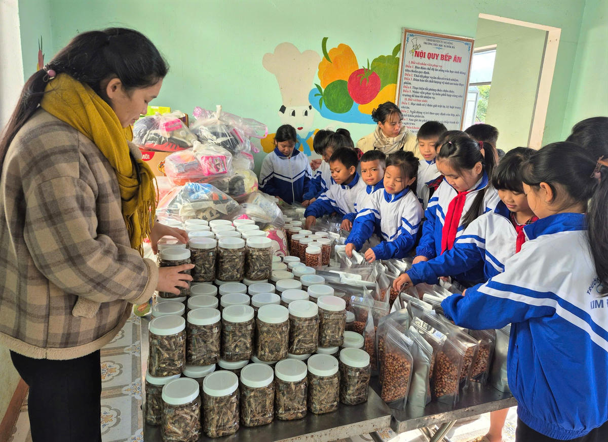 Cô giáo và học sinh của Trường Tiểu học Kim Đồng, xã Tu Mơ Rông cho cá khô, đậu phộng vào thẩu nhựa gửi tặng đồng bào vùng lũ. Ảnh: CV.