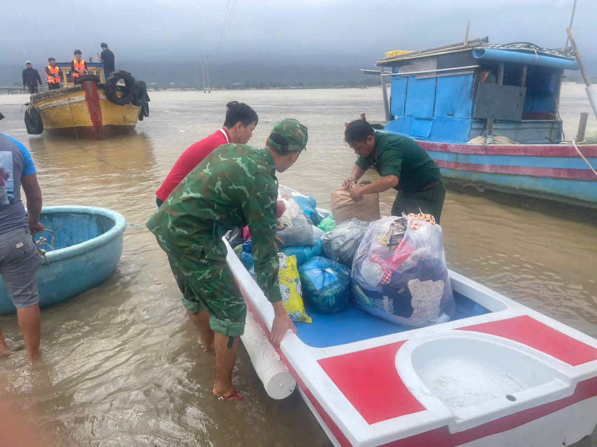 Bộ đội băng mình trong dòng nước lạnh mang từng thùng mì, từng chai nước uống đến cho bà con. Ảnh: BP.