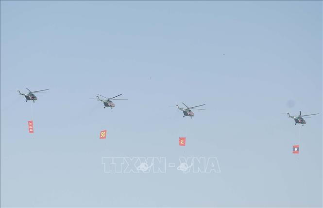 Biên đội máy bay trực thăng mang cờ bay trên bầu trời khu vực tổ chức lễ kỷ niệm. Ảnh: Thống Nhất/TTXVN