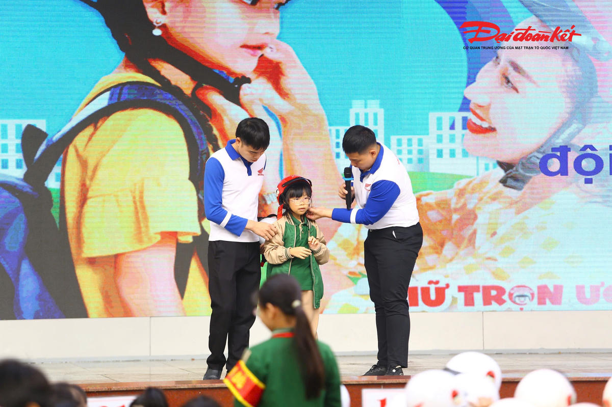 Báo cáo viên của Honda Việt Nam hướng dẫn các em đội mũ bảo hiểm đúng quy cách.