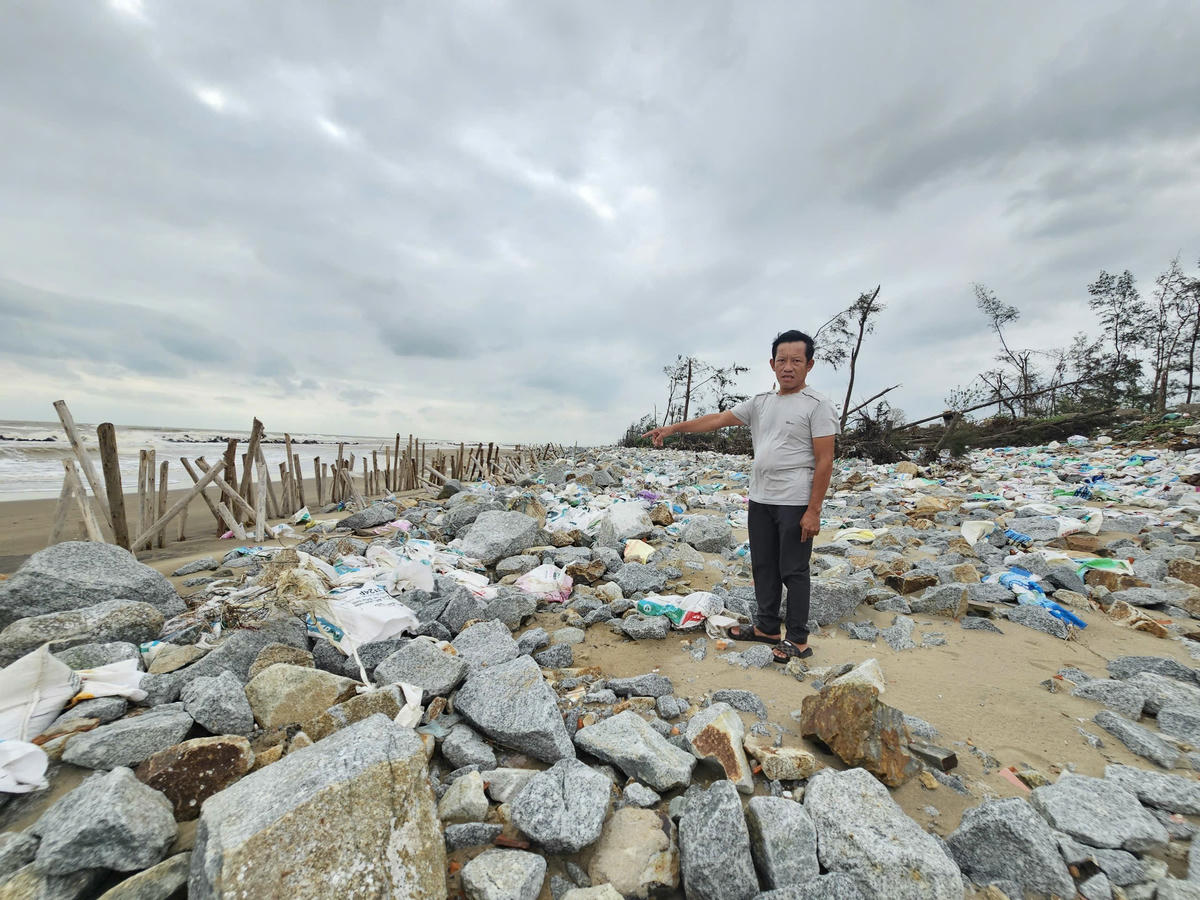 Ông Trần Văn Kế, 54 tuổi, thôn Tân Ninh Châu, xã Đan Hải đứng
giữa hàng ngàn bao tải cát và đá hộc “vá tạm đê” Hội Thống. Ảnh: Quốc Thanh.