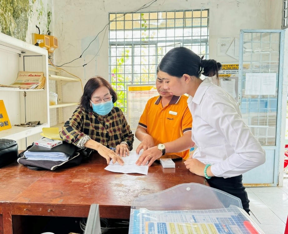 Nhân viên Ngân hàng LPBank và nhân viên Bưu điện vận động 
người thụ hưởng nhận lương hưu qua ATM. Ảnh: TT