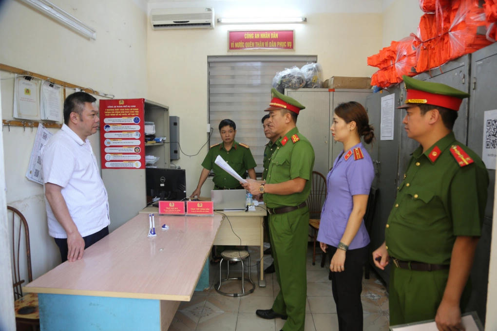 Ông Vũ Đình Kiên (áo trắng, bên trái) nghe đọc lệnh bắt tạm giam ngày 15/11/2024. Ảnh: Công an cung cấp.