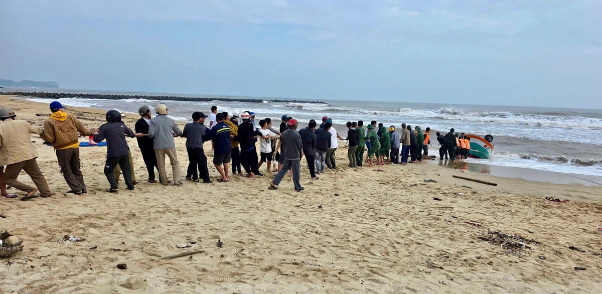 Cán bộ chiến sĩ Đồn Biên phòng cửa khẩu cảng Cửa Việt cùng các lực lượng, người dân tiến hành trục vớt tàu cá lên bờ. Ảnh: BP.