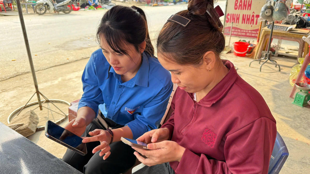 Thành viên Tổ Công nghệ số cộng đồng hướng dẫn người dân Hồng Thái tìm kiếm thông tin trên điện thoại thông minh. Ảnh: Đức Sơn