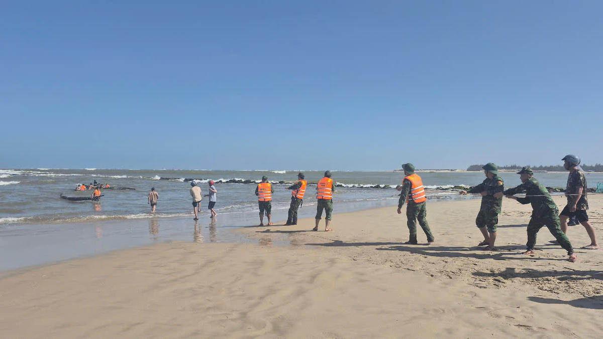 Cán bộ chiến sĩ Đồn Biên phòng cửa khẩu cảng Cửa Việt cùng các lực lượng, người dân kéo ghe bị chìm lên bờ. Ảnh: BP.