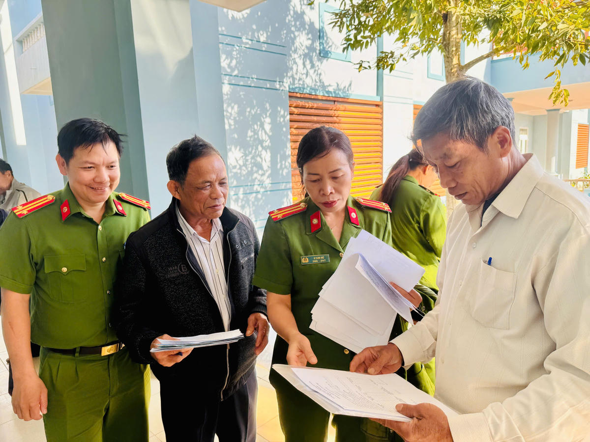 Công an phường Ea Cao hướng dẫn cho các hộ kinh doanh thực hiện các nội dung kí cam kết. Ảnh: Thanh Nga.