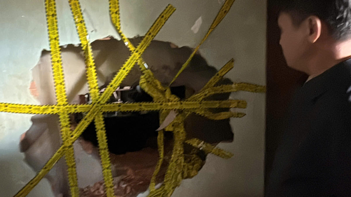 Lực lượng chức năng đục lỗ thủng từ nhà hàng xóm mới tiếp cận được vào bên trong để cứu người bị mắc kẹt. Ảnh: TT.