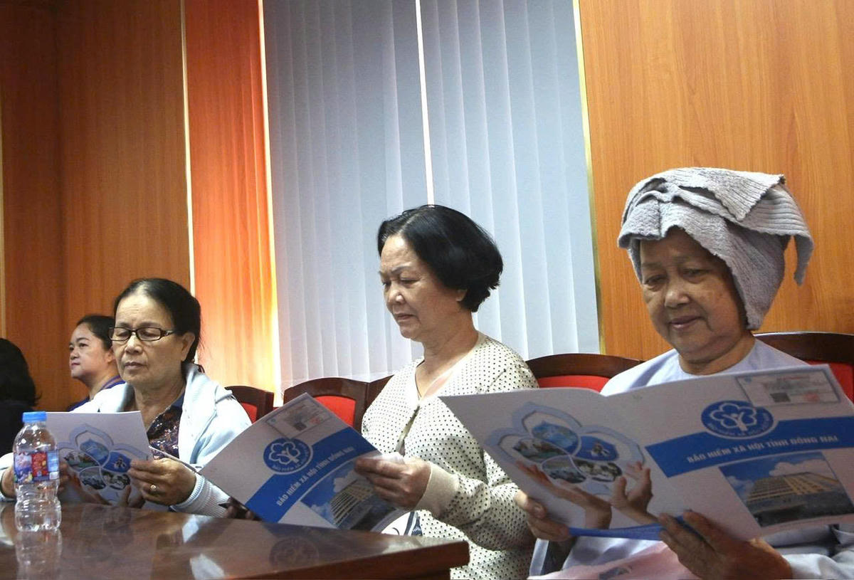 Người dân phấn khởi khi được nhận những tấm thẻ BHYT, sổ BHXH từ các mạnh thường quân. Ảnh: Hồ Tú.