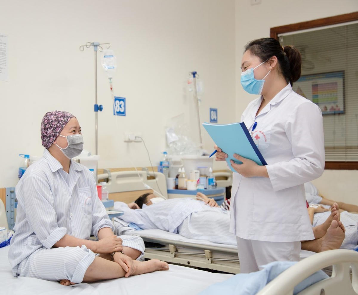 Nhân viên CTXH thăm hỏi người bệnh. Tiếp xúc với người bệnh hàng ngày và qua trao đổi với nhân viên y tế, nhân viên CTXH có thể phát hiện những trường hợp cần hỗ trợ tâm lý, xã hội. (ảnh H.L)

