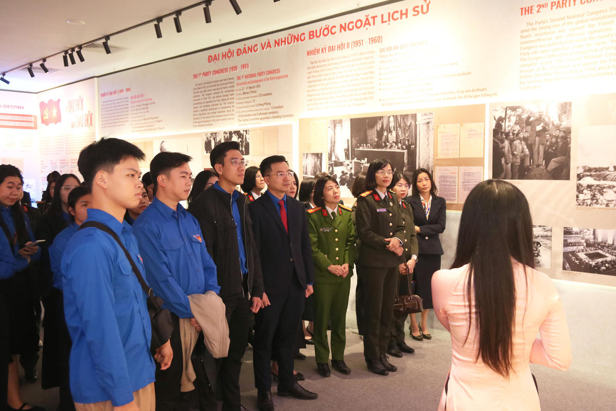 Các đại biểu nghe giới thiệu về các tài liệu, hình ảnh, hiện vật được trưng bày tại triển lãm.