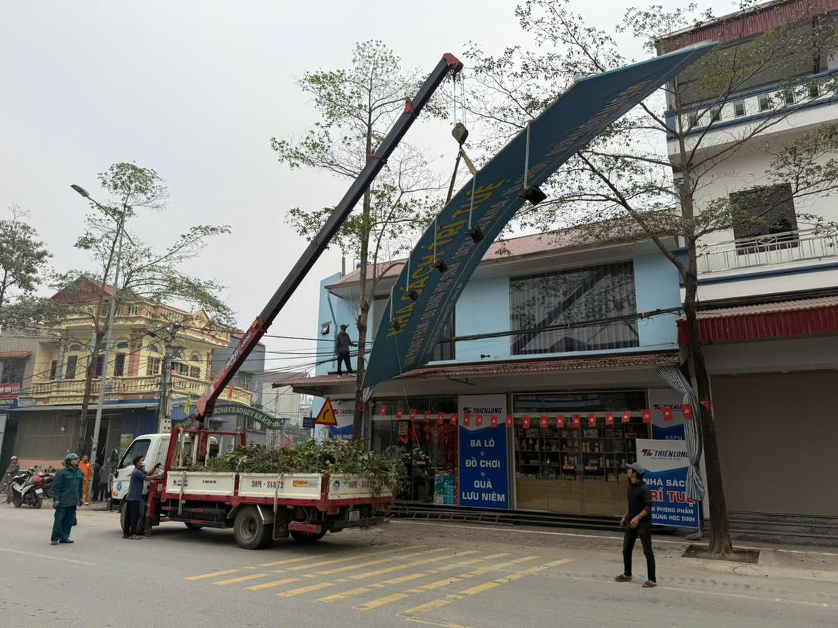 Lực lượng chức năng tháo dỡ biển quảng cáo vi phạm hành lang an toàn giao thông. Ảnh: T.L