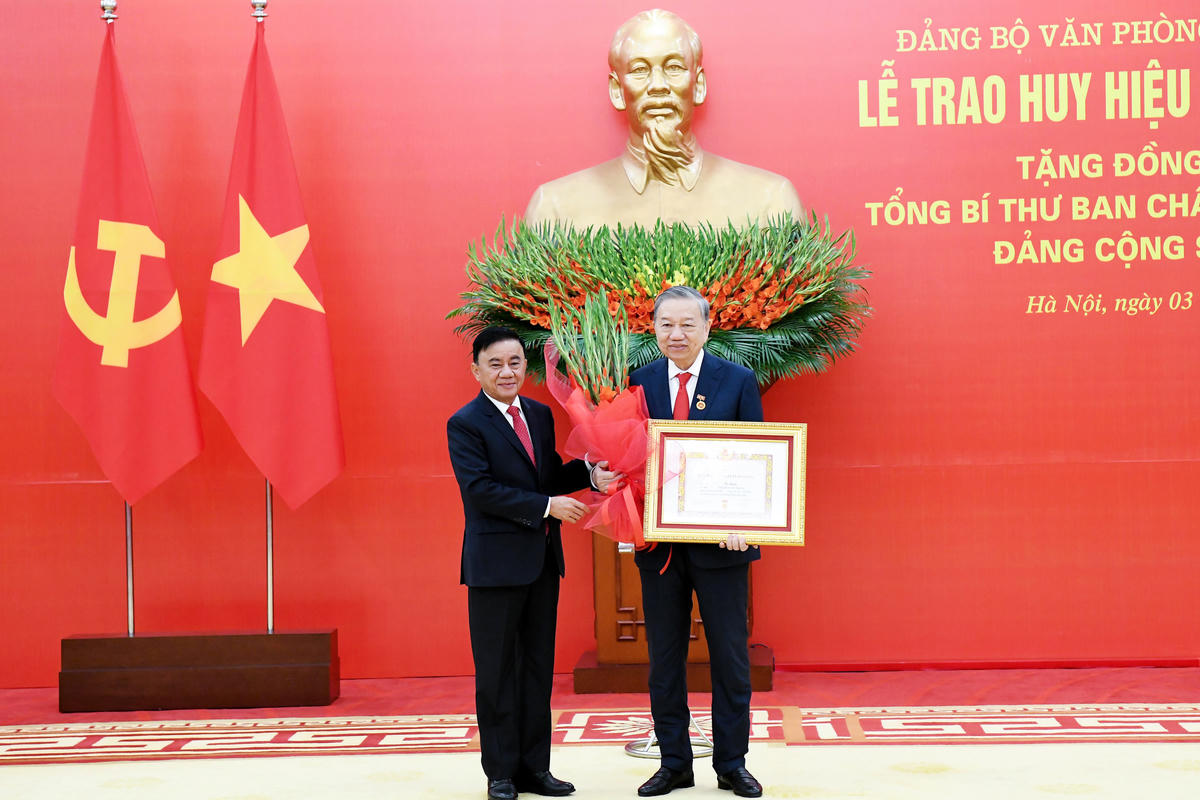 Thường trực Ban Bí thư Trần Cẩm Tú trao huy hiệu 45 năm tuổi Đảng và tặng hoa chúc mừng Tổng Bí thư Tô Lâm (Ảnh: Lâm Hiển)