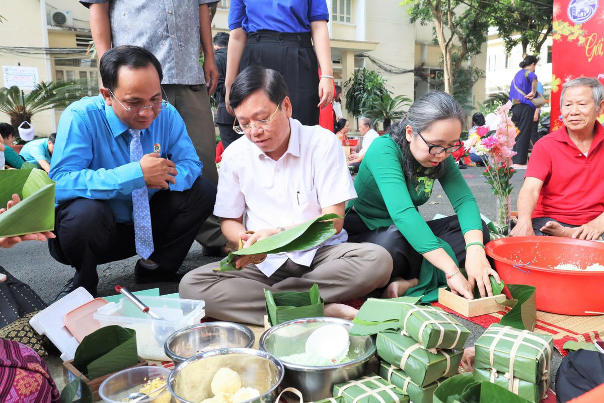 Ông Vũ Ngọc Tuất (áo trắng) - Bí thư Đảng ủy, Chủ tịch HĐND phường Bình Thạnh tham gia gói bánh cùng người dân. Ảnh: H.T