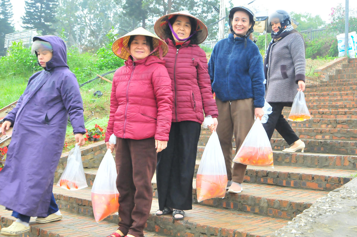 Nhiều người dân đem hàng chục cá chép đỏ thả xuống sông, cầu bình an, may mắn cho năm mới. Ảnh: Xuân Trường.
