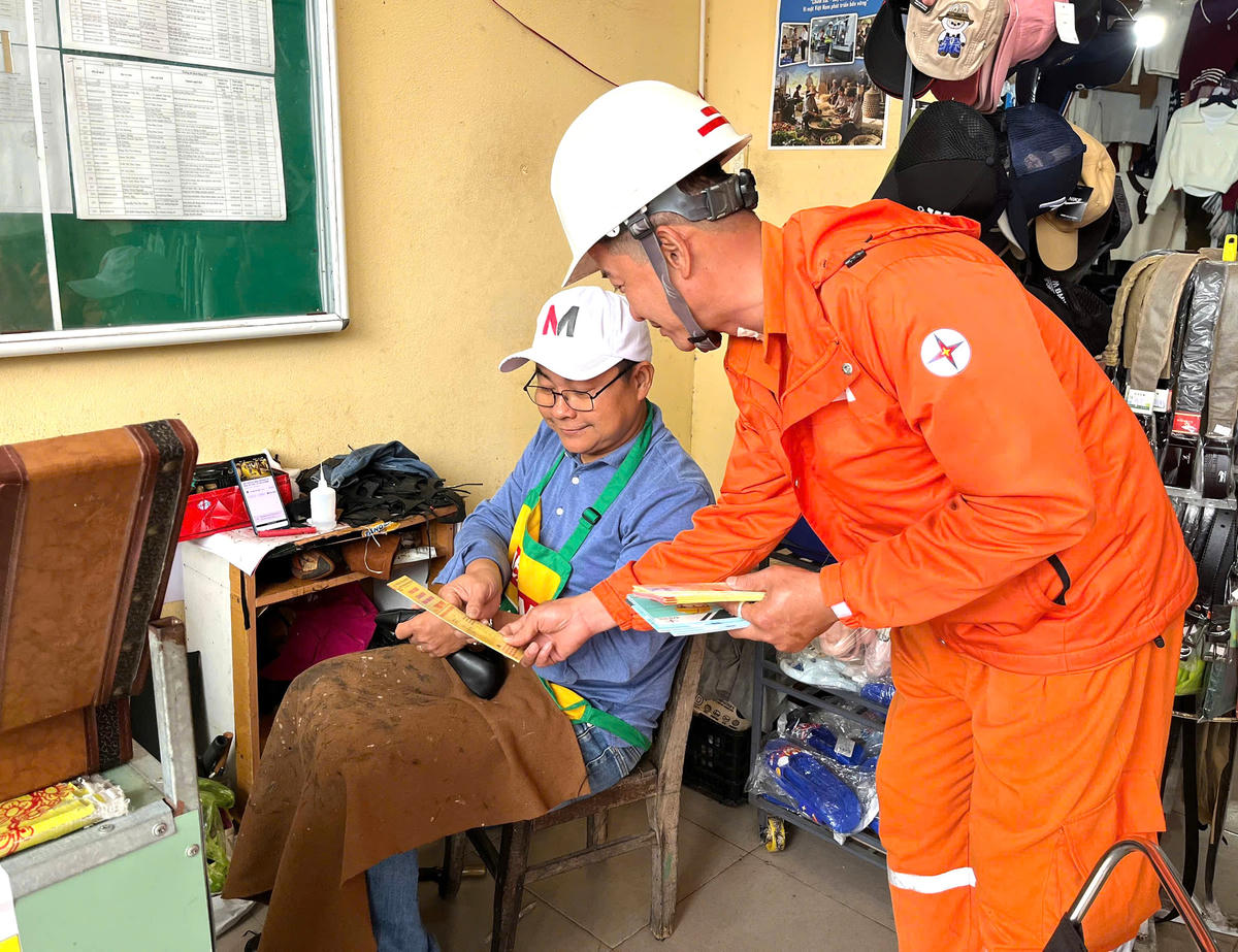 Nhân viên Đội Quản lý điện Cẩm Lệ tuyên truyền an toàn điện tại chợ Cẩm Lệ. Ảnh: Đức Lâm.