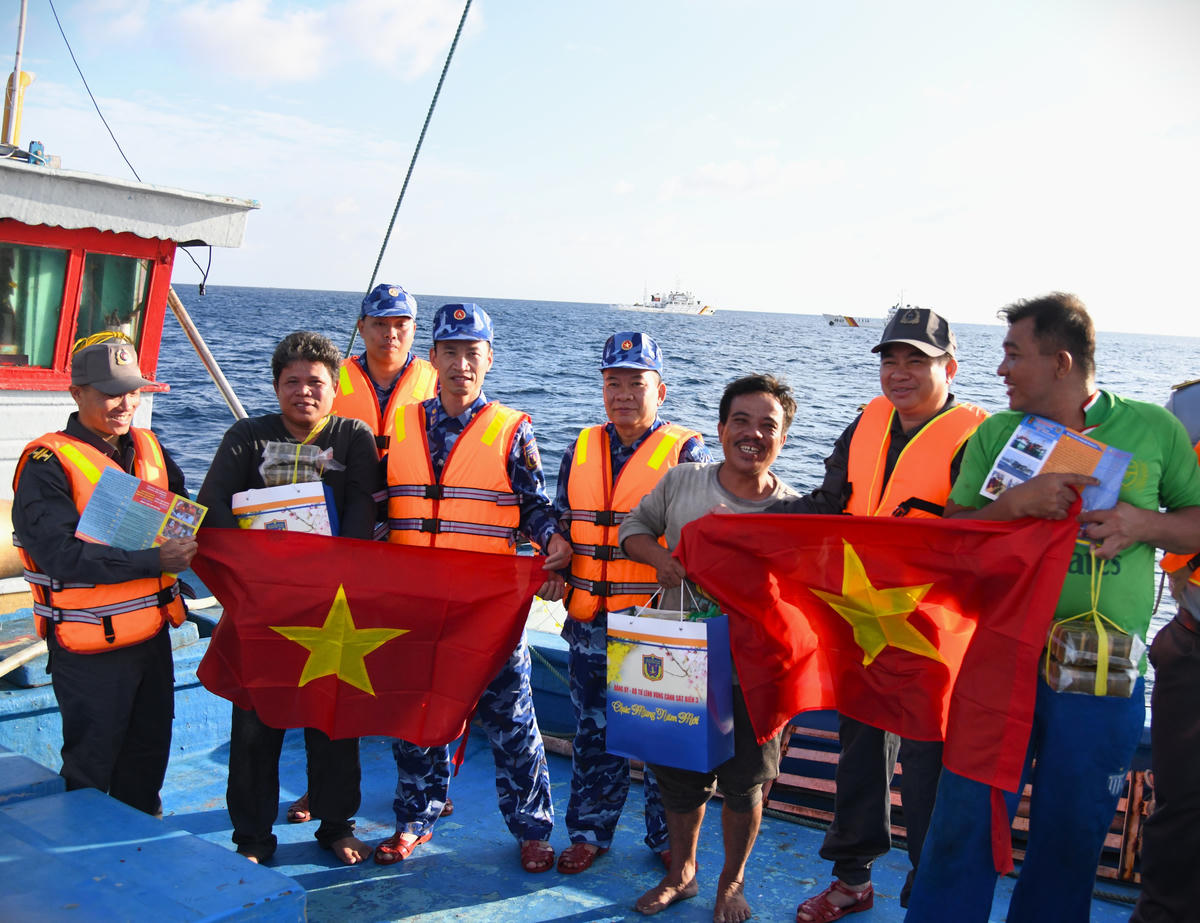 Đoàn công tác tặng cờ Tổ quốc, phát tờ rơi, tặng quà cho ngư dân. Ảnh: Đức Định.