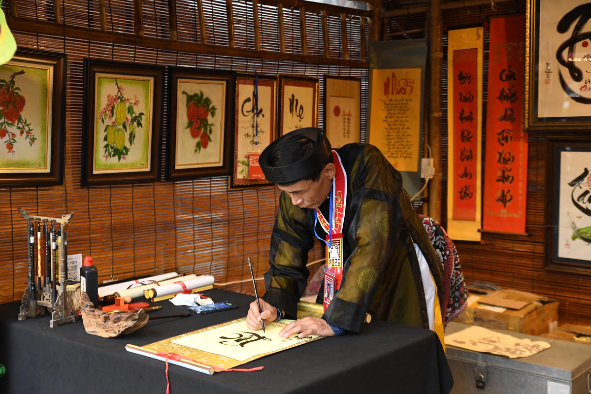 Ông đồ chăm chút từng nét bút. Ảnh: Phạm Sỹ..
