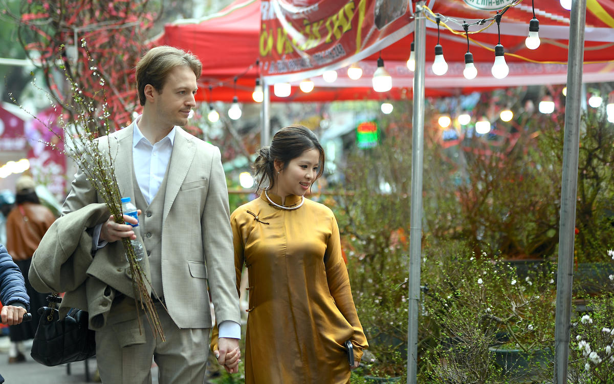 Tà áo dài thướt tha bên cành đào, chậu quất tạo nên bức tranh giao thoa giữa truyền thống và nhịp sống hiện đại. Ảnh: Phạm Sỹ.