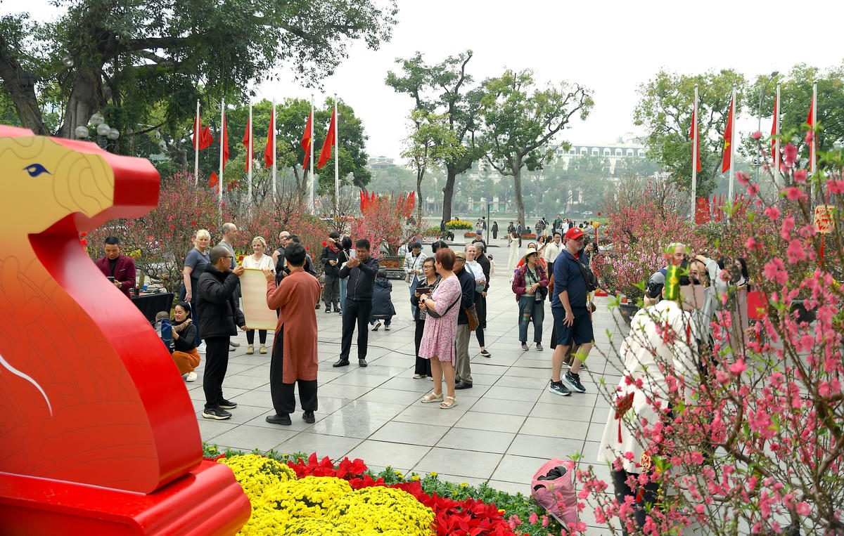 Người dân và du khách nô nức du xuân, thưởng ngoạn sắc hoa bên hồ Gươm. Ảnh: Phạm Sỹ.