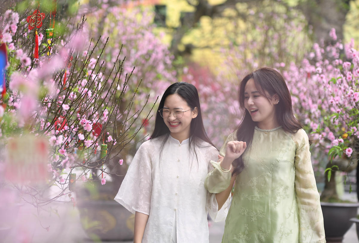 Giữa không gian hoa xuân ngập tràn sắc đào hồng, những nụ cười rạng rỡ của các cô gái như làm bức tranh mùa xuân thêm tươi mới. Ảnh: Phạm Sỹ..