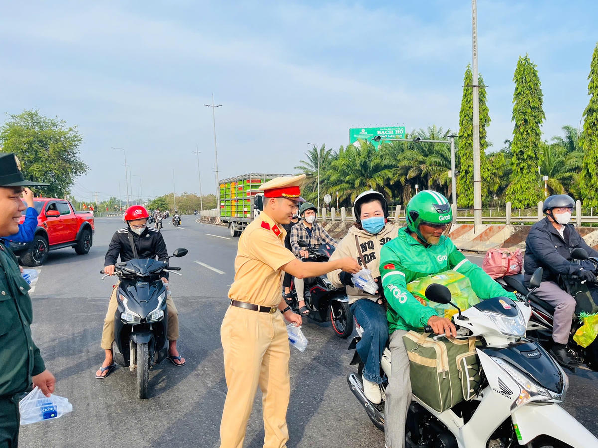 CSGT Công an tỉnh Vĩnh Long “đội nắng” xuống đường tặng nước suối phục vụ người dân về quê đón Tết. Ảnh: Trung Ngãi.