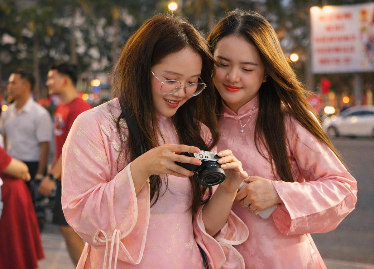 Nhóm bạn trẻ xem ảnh check in tại Quảng trường 24/3. Ảnh: Nguyễn Tín.