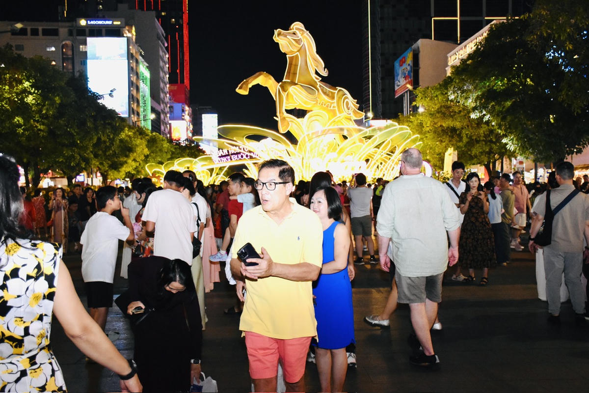 Người dân tìm về đường hoa Nguyễn Huệ để chụp hình chờ đợi thời khắc giao thừa. Ảnh: Thanh Thuỷ.