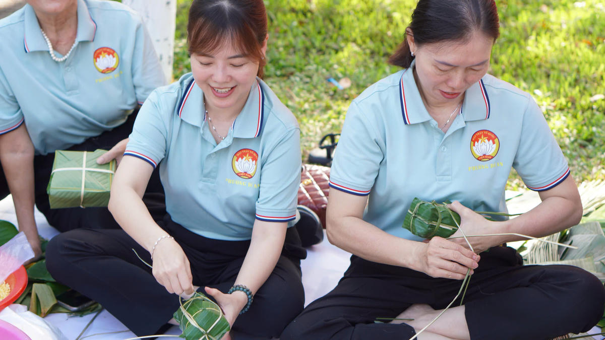 Chủ tịch Mặt trận phường Dĩ An bà Lâm Hoàng Thuỳ Trang (ngồi giữa) tự tay gói bánh chưng tặng người nghèo tại Ngày hội “Xuân đoàn kết - Tết Nghĩa tình” do phường tổ chức. Ảnh: Q.Đ.