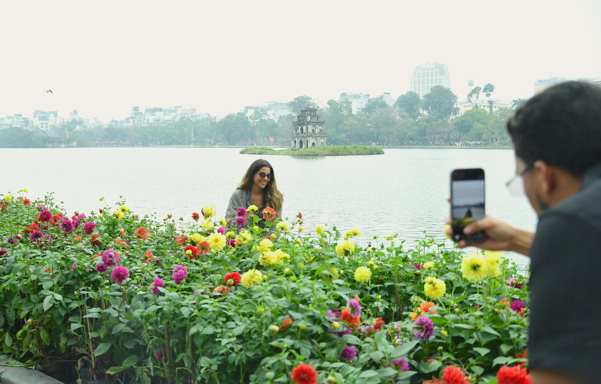 Du khách quốc tế lưu lại những khoảnh khắc sắc xuân bên Hồ Gươm. Ảnh: Phạm Sỹ.