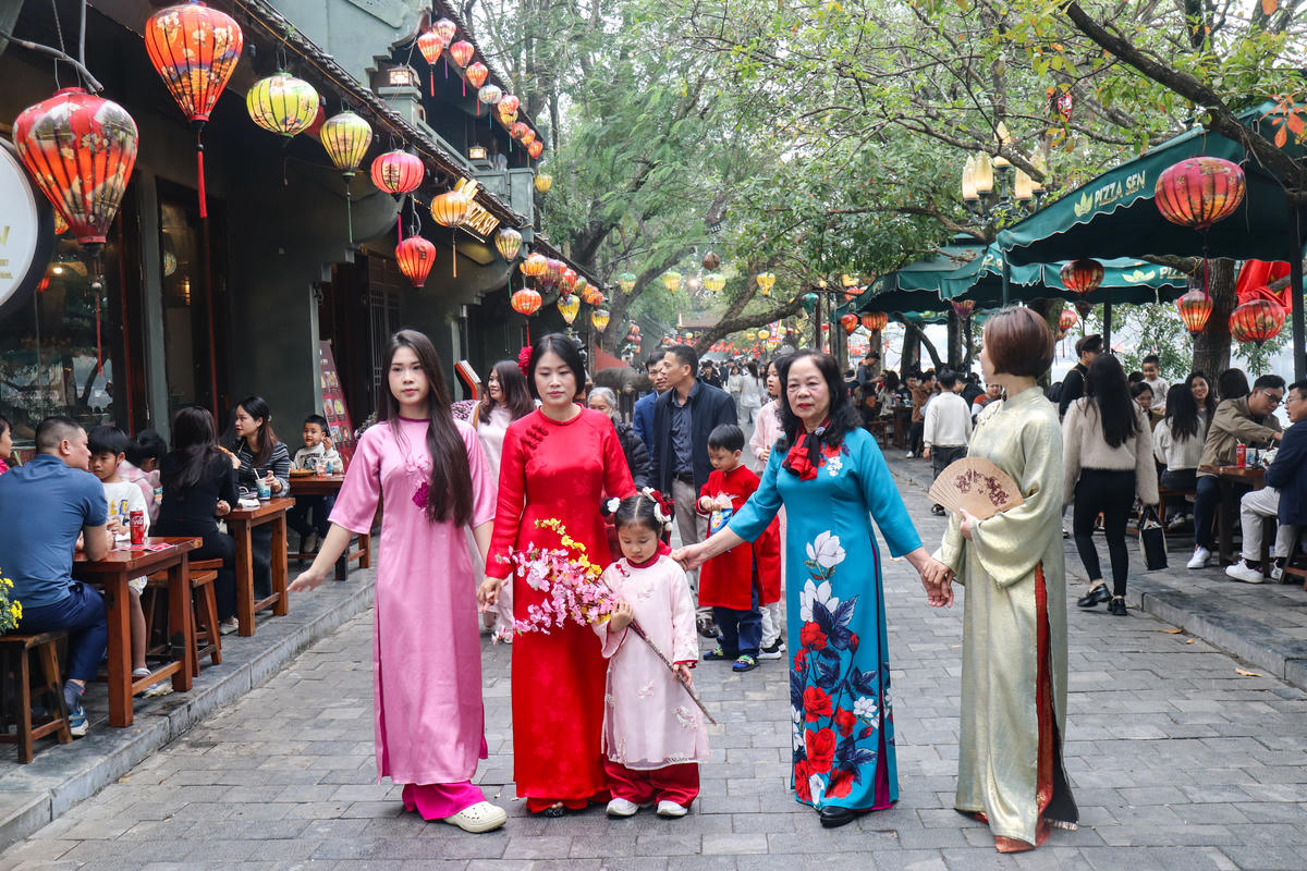 Không gian phố cổ được trang trí đậm sắc xuân với đèn lồng, câu đối đỏ, tiểu cảnh truyền thống. Các quán cà phê, gian hàng ẩm thực đông kín khách. Ảnh: Đình Minh