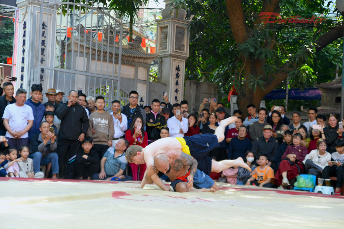Đô vật nước ngoài tự tin bước vào sới, mang theo phong cách thi đấu hiện đại, tạo nên màn so tài đa sắc màu văn hóa. Sự hiện diện của các vận động viên quốc tế góp phần khẳng định uy tín và sức hút ngày càng rộng mở của hội vật Mai Động. Ảnh: Phạm Sỹ.