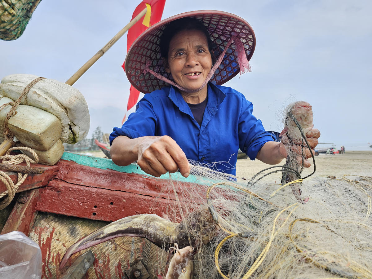 Bà Hồng, 56 tuổi, ở xã Tiên Điền, tỉnh Hà Tĩnh đang gỡ cá ngát trúng lưới sau chuyến ra khơi của chồng. Ảnh: Quốc Thanh