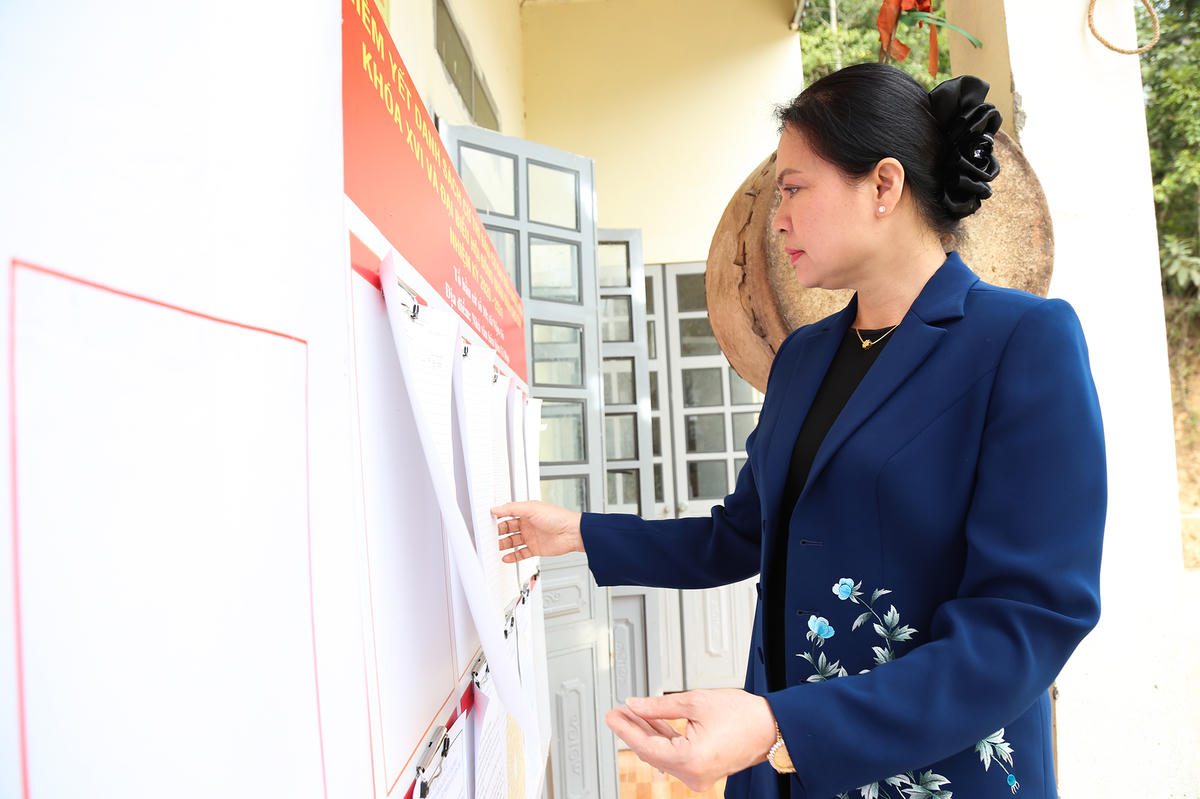 Bà Hà Thị Nga lật giở xem từng trang danh sách các cử tri được niêm yết công khai.