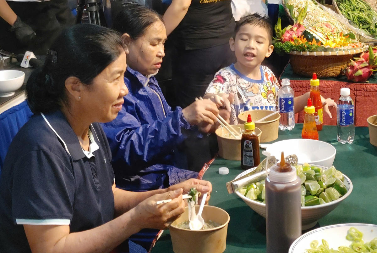 Người dân và công dân mặc áo mưa đi ăn phở miễn phí. Ảnh: H.L