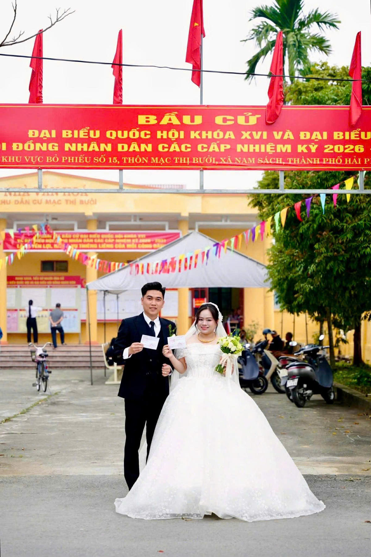 Đôi vợ chồng trẻ đã cùng nhau chụp ảnh lưu niệm tại cổng khu vực bầu cử, lưu giữ dấu ấn đặc biệt của một ngày vừa thiêng liêng đối với cuộc đời họ. Ảnh: TĐ.&nbsp;