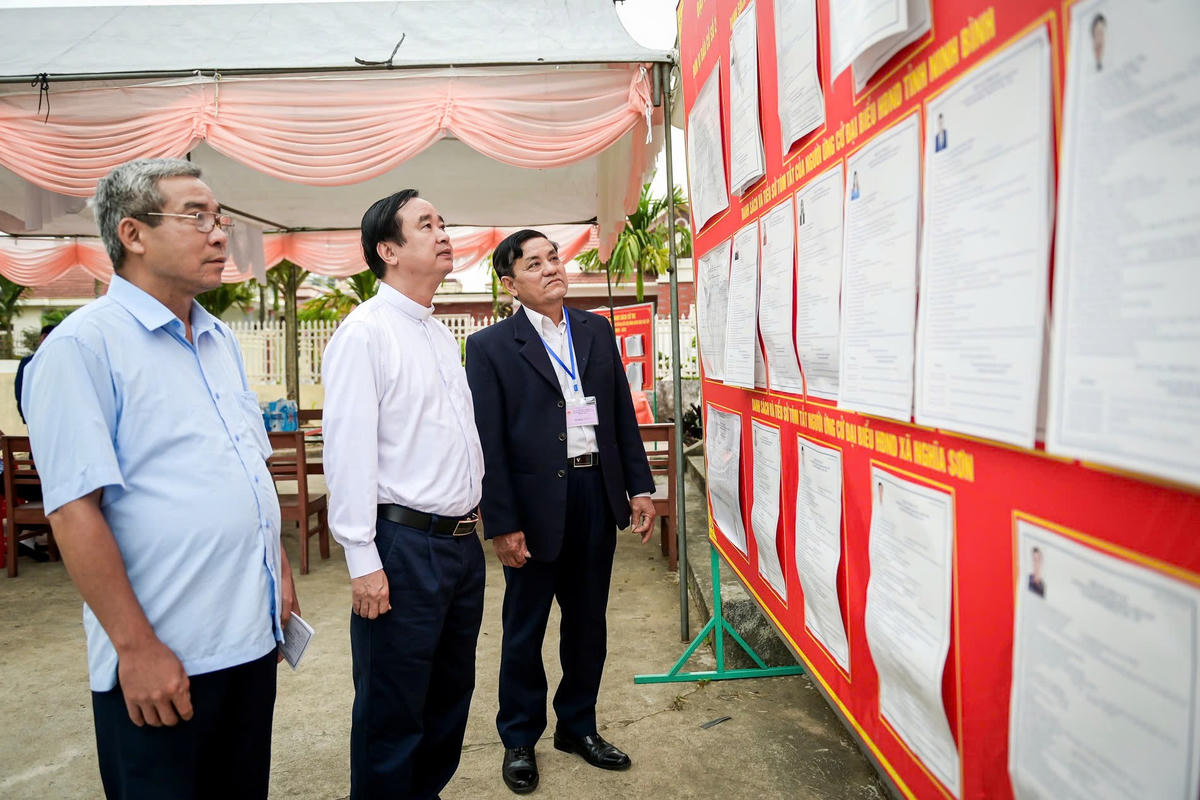 Cử tri theo dõi danh sách các ứng cử viên tại khu vực bỏ phiếu số 3, xã Nghĩa Sơn. Ảnh: Trọng Tùng