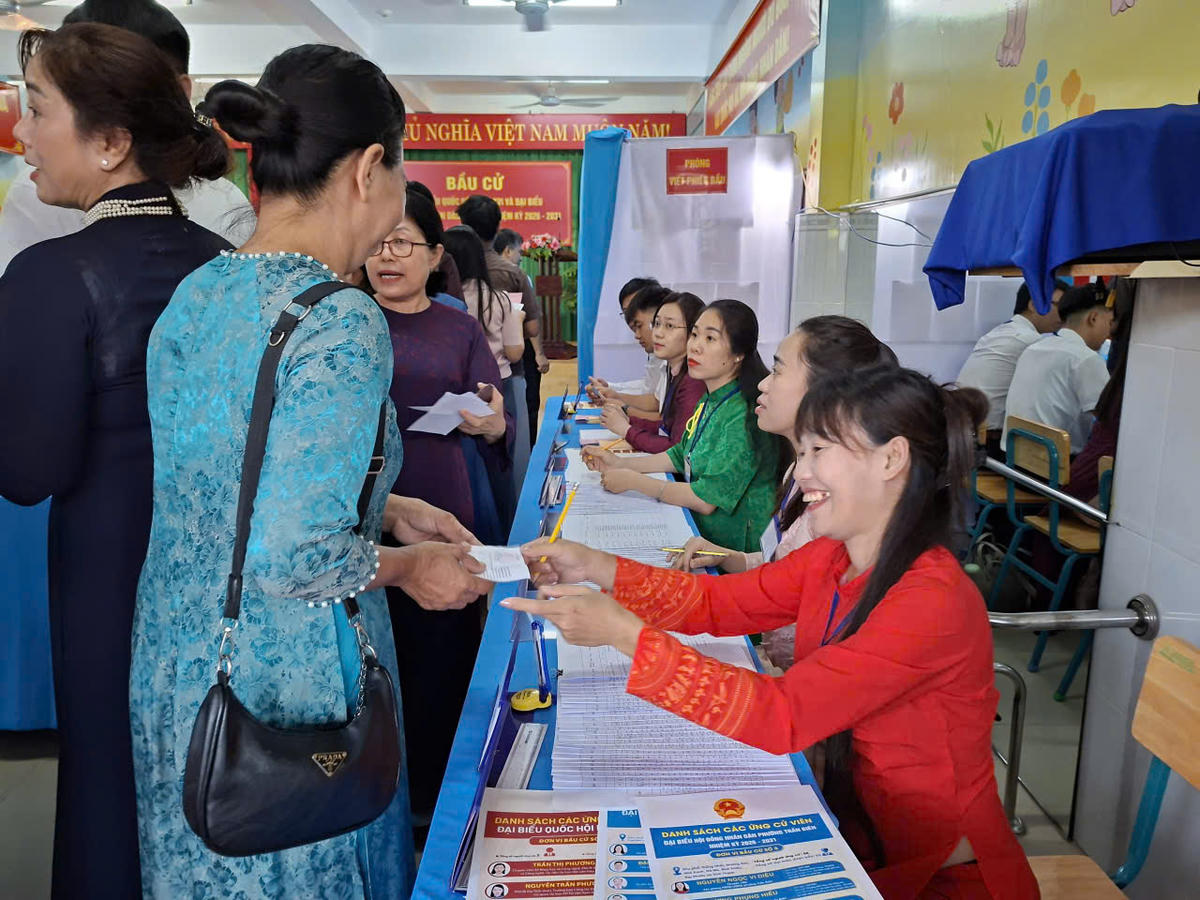 Người dân trong trang phục chỉnh tề nhận phiếu để tiến hành thủ tục bầu cử. Ảnh: S.X