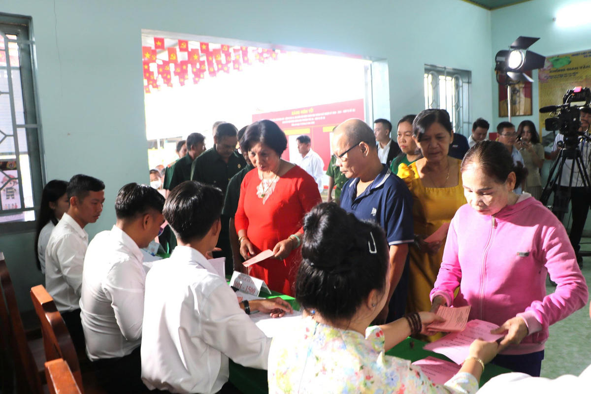 Ông Nguyễn Minh Triết, ông Võ Văn Minh và các cử tri phường Phú An làm các thủ tục trước giờ bỏ phiếu. Ảnh: LA.